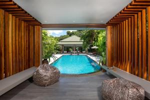 卡伦海滩Karon Beach Pool Villa - Sha Extra Plus的一座室内游泳池,位于一座带两把椅子的房子里