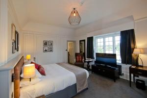 莱瑟黑德德维尔场馆霍斯利公园酒店的一间卧室配有一张床、一张书桌和一台电视