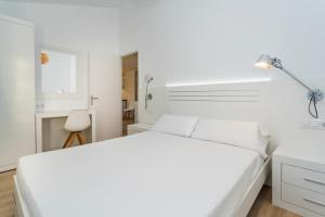 休达德亚Apartaments Cales de Ponent的白色卧室配有白色的床和灯