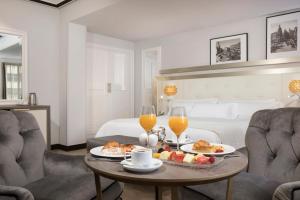 马德里卡斯蒂利亚美利亚酒店的一间房间,配有一张桌子,提供食物和两杯橙汁