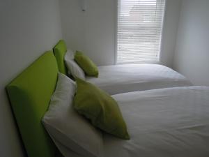 朴次茅斯Pretty Victorian Cottage的一间卧室配有两张带绿色枕头的床和窗户。