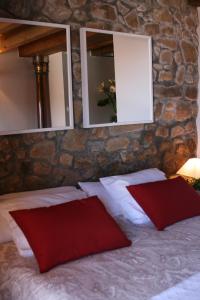 拉斯特雷斯Casa rural La Casona del Piquero的一张带两个红色枕头和两个镜子的床