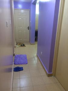 内罗毕朴穆兹卡公寓的走廊上设有紫色门,铺着瓷砖地板