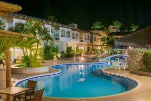 塞古罗港普拉亚萨拉纳酒店 的夜间带桌椅的度假村游泳池
