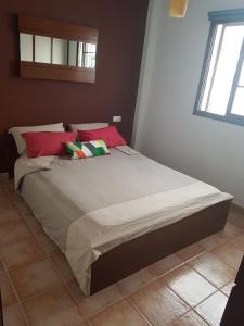 阿列塔Casa Garita Beach的卧室内的一张床位,配有红色和绿色枕头