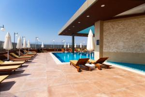 安塔利亚SKY Business Hotel的酒店游泳池设有躺椅和遮阳伞