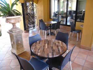 凯恩斯凯恩斯皇家棕榈酒店的一间设有桌椅的餐厅,以及一间种植了植物的餐厅