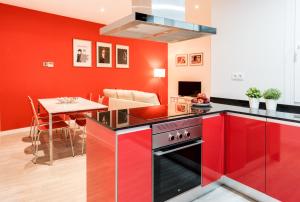 马德里古兹曼生活公寓的一间带红色橱柜的厨房和一间带桌子的用餐室