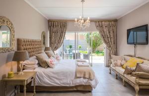 比勒陀利亚La Vida Luka - Luxury Guesthouse的一间卧室配有一张床、一张沙发和一台电视。