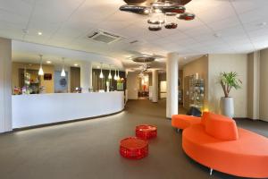 索肖B&B HOTEL Montbéliard-Sochaux的一个带橙色沙发和柜台的办公大厅