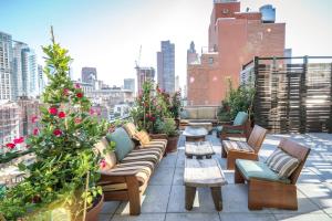纽约梅德酒店的屋顶庭院配有沙发、桌子和鲜花