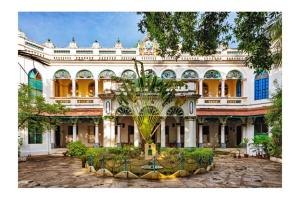 KānādukāttānChettinadu Mansion – An Authentic Heritage Palace的一座大建筑,前面有棕榈树