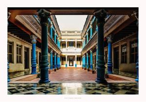 KānādukāttānChettinadu Mansion – An Authentic Heritage Palace的蓝色柱子的古老建筑的走廊