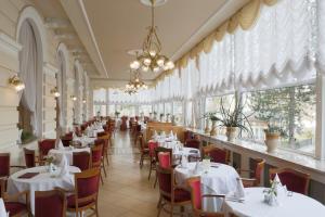 卡罗维发利布里斯托尔酒店的餐厅设有白色的桌椅和窗户。