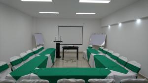 马那瓜Hotel Brandts Ejecutivo Los Robles的一间会议室,配有绿色和白色的椅子和屏幕