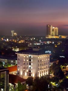 泗水Amaris Hotel Darmo Surabaya的夜幕降临的城市前的一座建筑