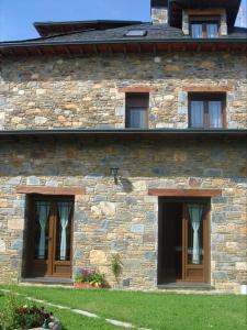 LinarejosHotel Rural El Caseron de Linarejos的一座石头建筑,两边有三个窗户