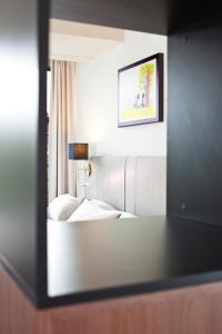 阿姆斯特丹Hapimag Apartments Amsterdam的镜子反射在酒店房间的床