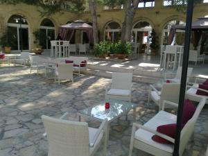 莱乌卡Messapia Hotel Resort的庭院配有白色的椅子和一张带蜡烛的桌子。