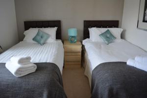 格拉斯哥Glasgow Hampden House的卧室内的两张床,配有两条毛巾