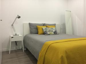 里斯本Lisboa Comfort Apartment的一间卧室配有一张带黄色枕头和灯的床。