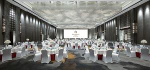 郑州郑州富力万达文华酒店 的宴会厅配有白色的桌椅和屏幕