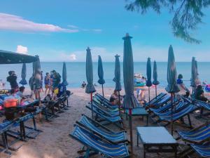 七岩七岩山姆度假酒店的一群人坐在海滩上的椅子上,拿着遮阳伞
