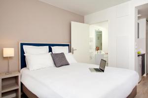 巴黎巴黎戴夫住宿及商务公寓酒店的一间卧室配有一张白色的床,上面有笔记本电脑