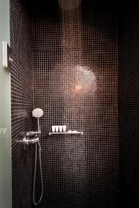 易莫洛林乐基纳马累酒店-仅限成人入住的黑色瓷砖浴室配有淋浴和淋浴喷头