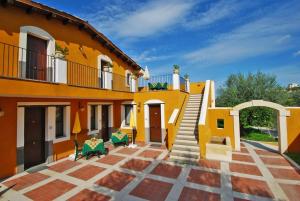 卡尔伦蒂尼里卡蒂亚农场酒店的大型黄色房屋设有楼梯和庭院