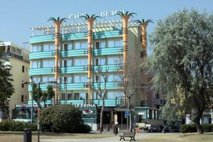 里米尼Hotel Palm Beach B&B SEA VIEW的一座棕榈树环绕的大建筑