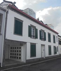 富尔纳斯Apartamento Silveira的白色的建筑,在街上有绿色百叶窗