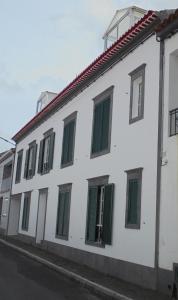 富尔纳斯Apartamento Silveira的白色的建筑,街道上设有绿色的窗户