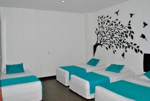 圣罗莎德卡瓦尔Hotel Los Cristales的一间设有三张床的客房,墙上有一棵树