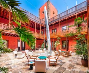 加拉奇科圣罗克酒店的红色建筑的庭院,配有桌椅