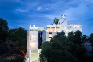 科钦Sidra Pristine Hotel and Portico Halls的一座白色的建筑,上面有棕榈树
