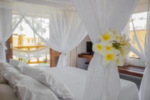 莫罗圣保罗Villa dos Corais的卧室配有白色窗帘和黄色鲜花。