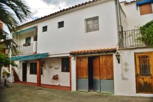 AlturaCasa Las Violetas的白色的房子,设有木门和庭院