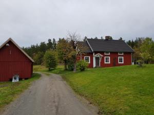 MaramöGärdesgården Lillstugan的土路上的一座红房子和一座红谷仓