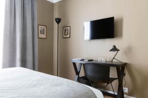 巴黎香榭丽舍大道马西斯酒店的一间卧室配有书桌,墙上配有电视