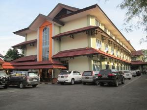 坤甸坤甸梅尔帕提酒店的停车场内有车辆的建筑物