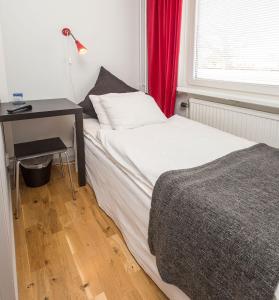 Alsterbro阿尔斯特布诺迷你酒店的一间卧室配有一张床和一张带红色窗帘的书桌