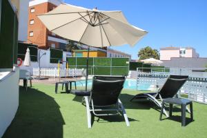 梅里达Deluxe Hostels & Suites Merida的游泳池旁配有遮阳伞的桌椅