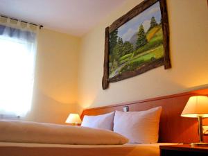 戈斯拉尔哈兹洛奇酒店的酒店客房设有一张床,墙上挂有绘画作品