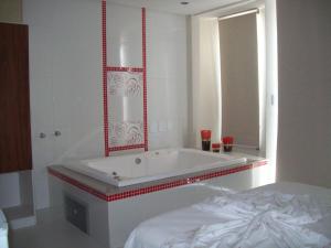 泰谢拉迪弗雷塔斯Hotel Milla的一间带镜子和床的浴缸的浴室