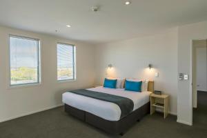 基督城Quest Cathedral Junction Serviced Apartments的一间卧室配有一张带蓝色枕头的大床