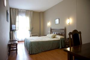 比利亚拉尔沃奥蕾莉亚之家酒店的一间卧室配有一张床、一张桌子和一个窗户。