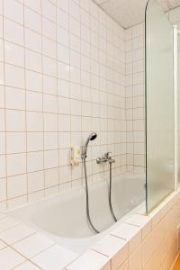 伊钦Hotel Rieger Garni的瓷砖浴室设有带淋浴的浴缸。