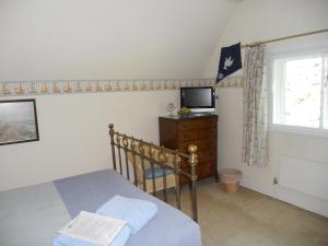 艾尔斯伯里Mayertorne Cottage的一间卧室设有一张床、一台电视和一个窗口。