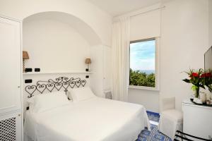 阿马尔菲极光酒店的白色的卧室设有白色的床和窗户。